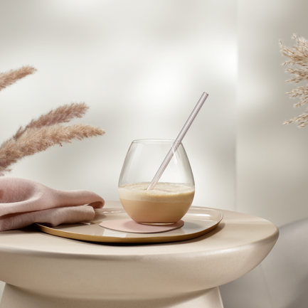 Ein eleganter Tisch mit einem Glas, einer Serviette und dekorativen Pampasgrassträußen in einem hellen Raum.