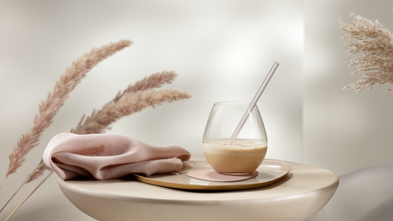 Ein eleganter Tisch mit einem Glas, einer Serviette und dekorativen Pampasgrassträußen in einem hellen Raum.