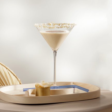 Das Bild zeigt einen cremigen Cocktail in einem Martini-Glas, umgeben von einem modernen, minimalistischen Ambiente.