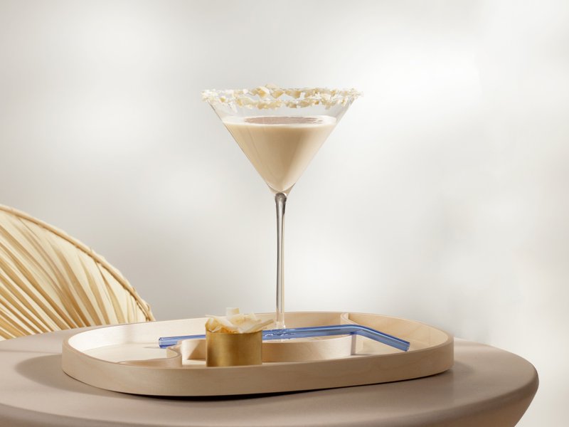 Das Bild zeigt einen cremigen Cocktail in einem Martini-Glas, umgeben von einem modernen, minimalistischen Ambiente.