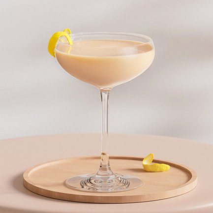Ein elegantes Cocktailglas mit einer cremigen, hellen Flüssigkeit und einer Zitronenschale auf einem Holztablett.