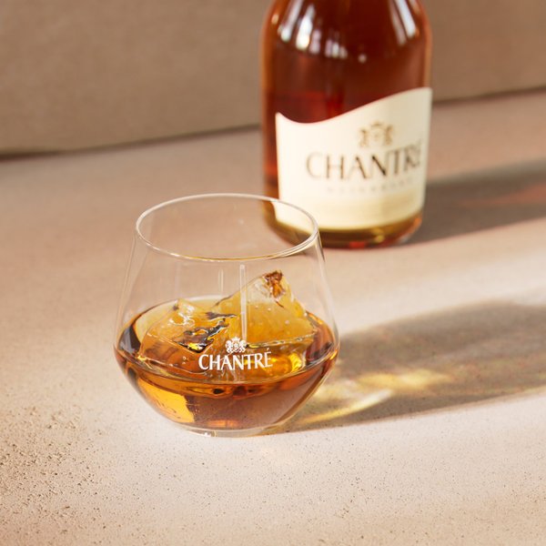 Chantré Weinbrand auf Eis im Glas, mit Flasche im Hintergrund.