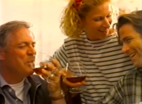 Ein Mann und eine Frau heben ihre Gläser an, während ein weiterer Mann lächelt und die fröhliche Stimmung genießt.