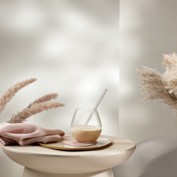 Ein eleganter Tisch mit einem Glas, einer Serviette und dekorativen Pampasgrassträußen in einem hellen Raum.